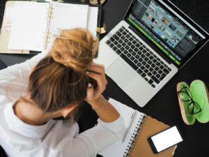 Vue aérienne d'une femme stressée travaillant à un bureau avec un ordinateur portable, un téléphone et des cahiers.