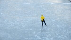 2 person in yellow jacket and black pants walking on snow covered ground during daytime