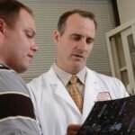 man in white dress shirt holding black tablet computer