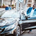 man in blue suit standing beside black car