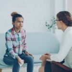A woman talks to a therapist in an office.