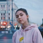 woman in pink hoodie standing near building during daytime