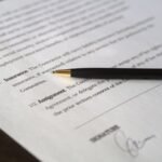 Document avec stylo et signature manuscrite, texte flou en arrière-plan