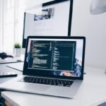 Un bureau moderne avec ordinateur affichant du code et accessoires